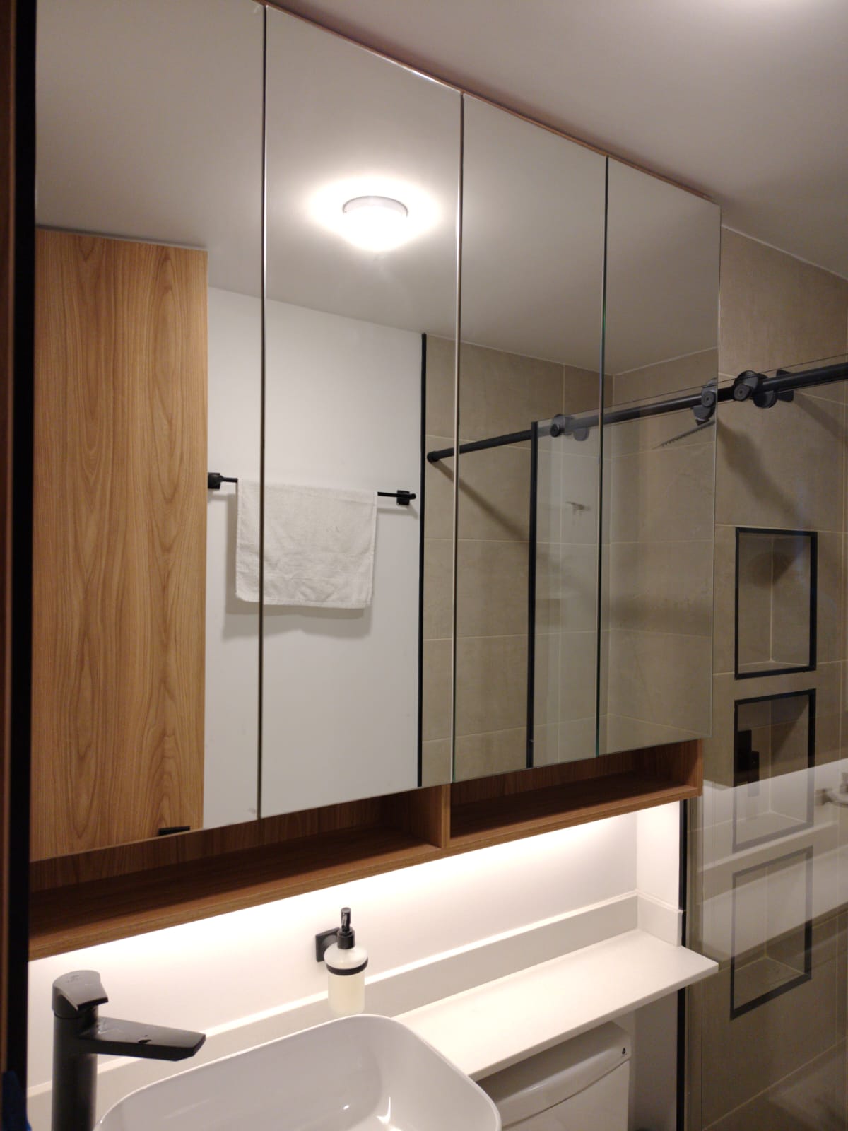 Gabinete de baño con puertas en espejo, nicho en madera e iluminación LED