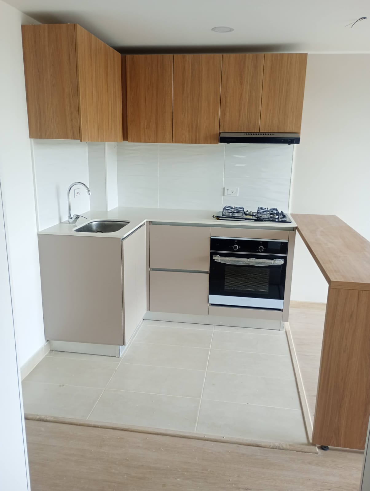 Cocina integral en L con altos en madera, bajos beige y barra auxiliar