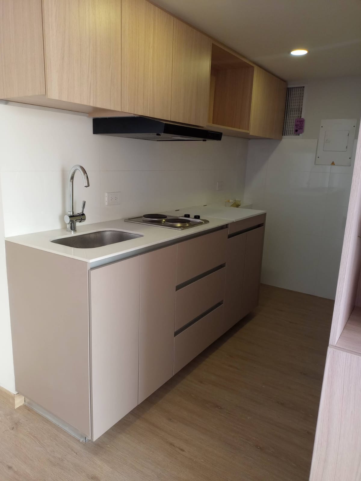 Cocina integral lineal con muebles altos en madera clara y bajos en beige