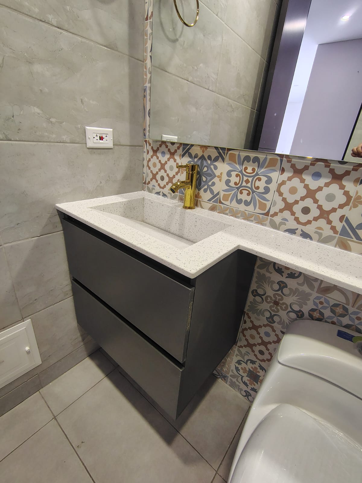 Mueble de baño gris con mesón en cuarzo blanco y enchape decorativo