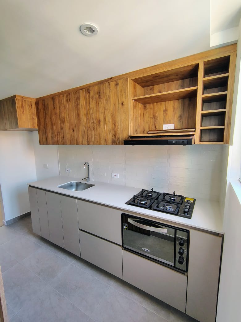 Cocina integral lineal con muebles altos en madera y bajos en gris con mesón blanco