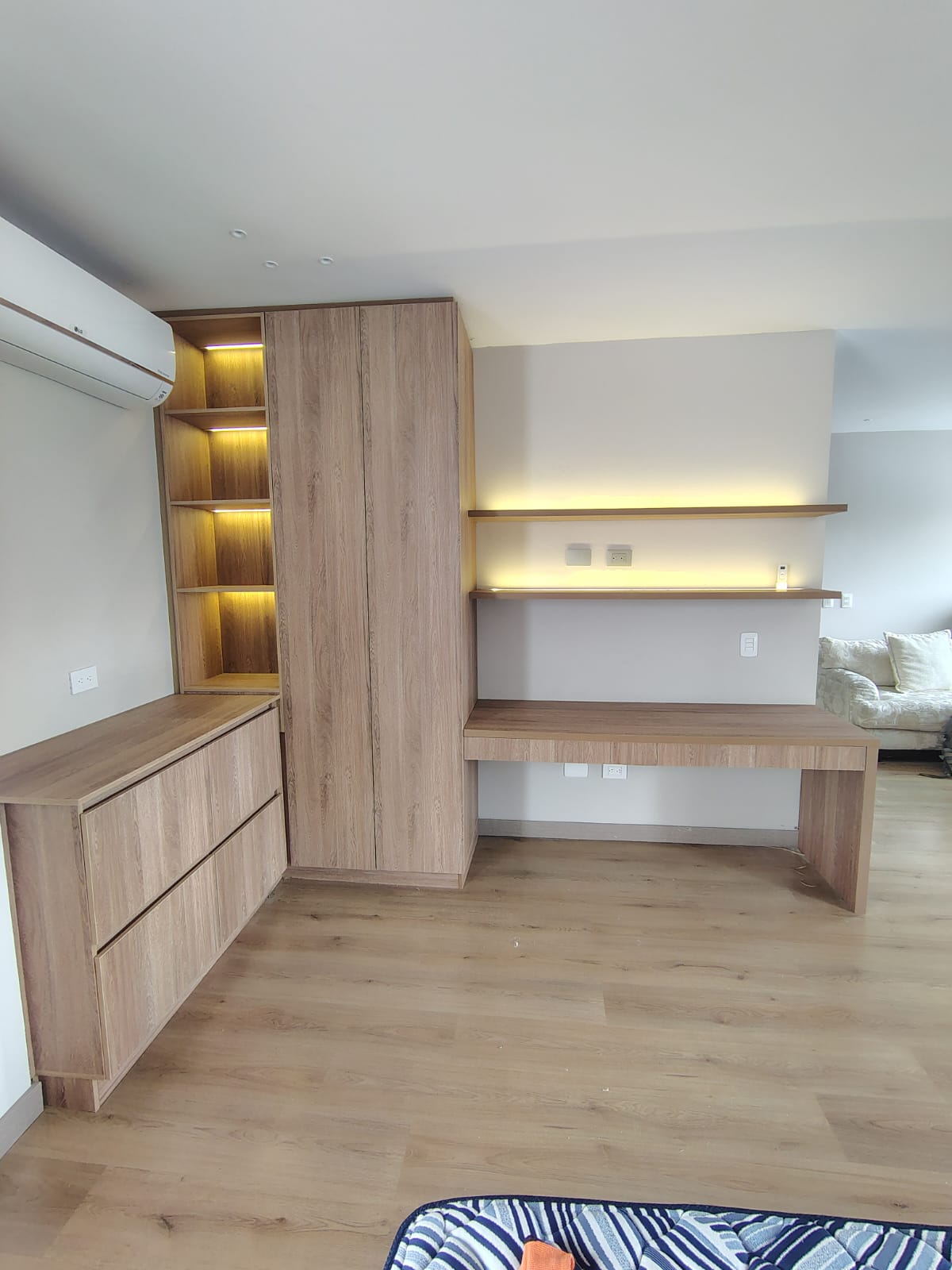 Clóset con escritorio integrado, repisas iluminadas y cómoda en madera