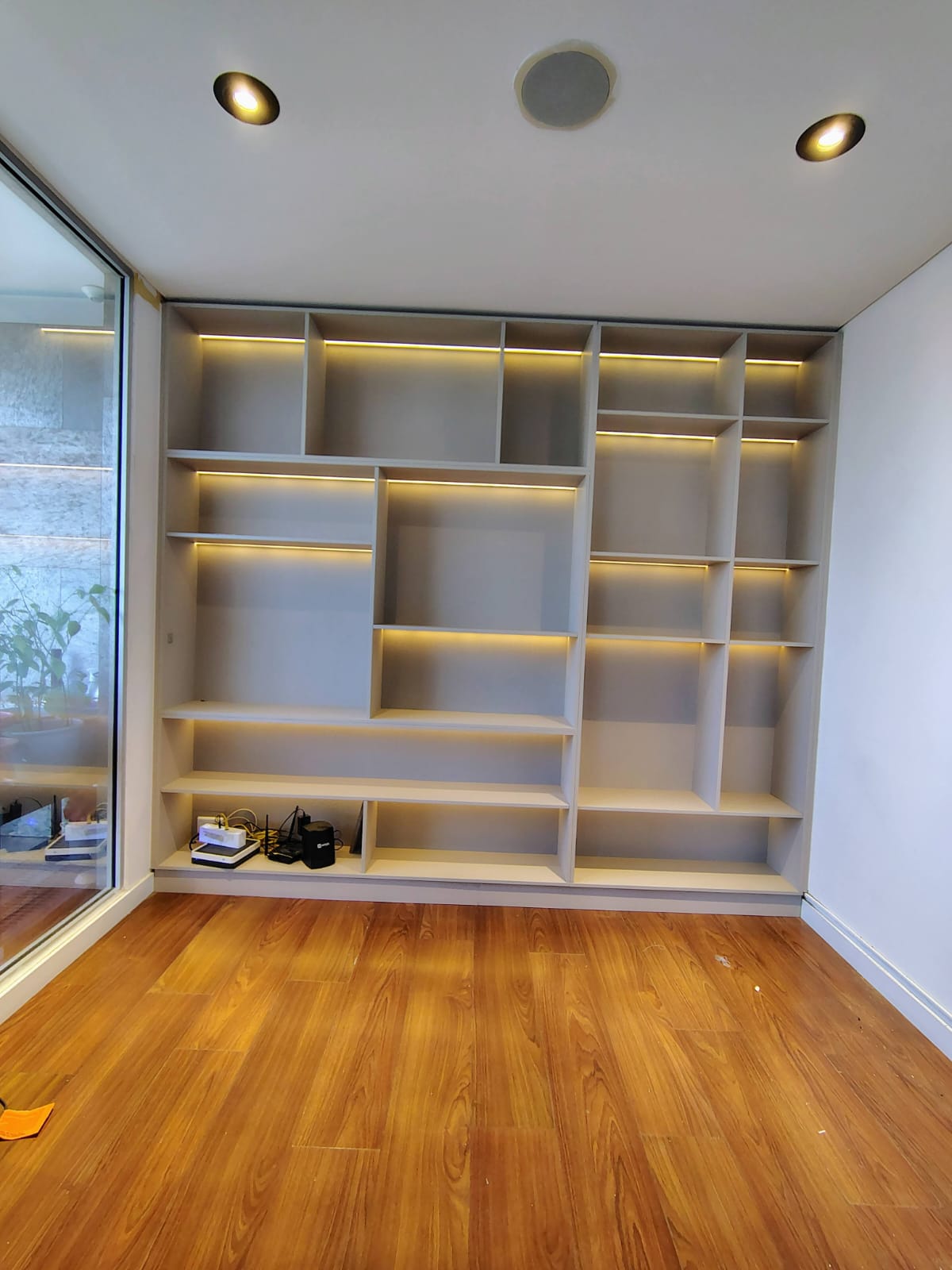 Biblioteca a medida en gris con entrepaños iluminados con LED