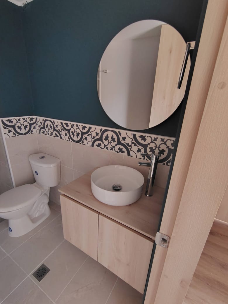 Mueble de baño flotante en madera con lavamanos de vasija y espejo redondo